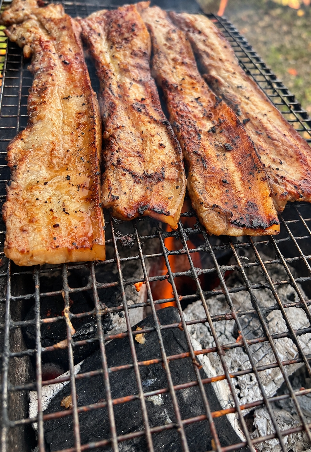 Liempo grilling over open charcoal in Melbourne