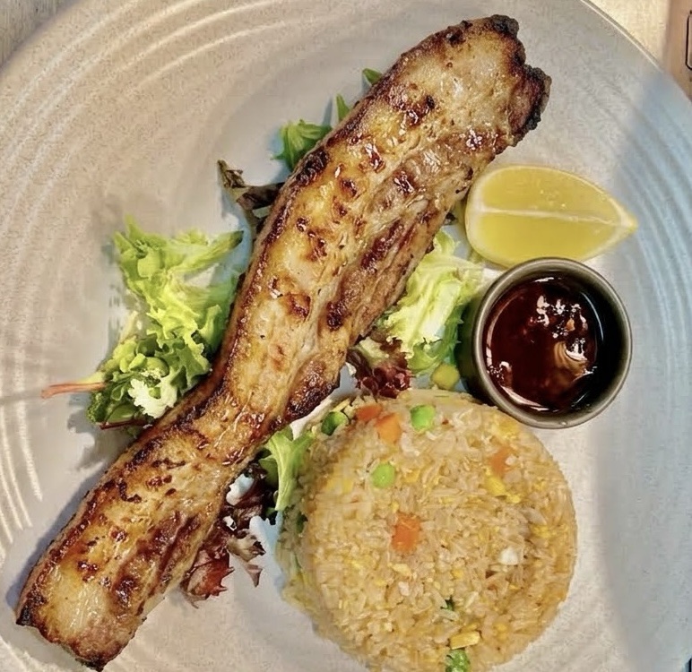 Grilled inihaw na liempo served with fried rice, a dipping sauce and a lemon wedge