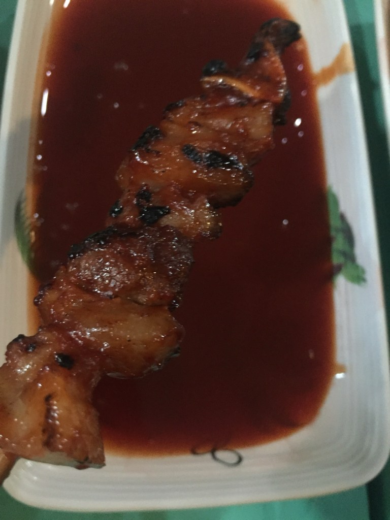 A skewer fresh off the grill dipped in sweet sauce
