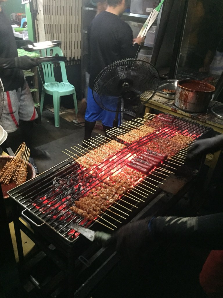 Skewers of BBQ, isaw and hotdog grilling over charcoal at Mang Raul's